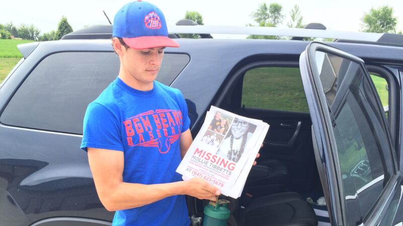 Scott Tibbetts, brother of the missing college student, holds informational posters he planned...
