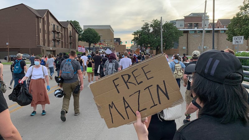 A marcher holds a sign that reads "Free Mazin," referring to one of the Iowa Freedom Riders'...