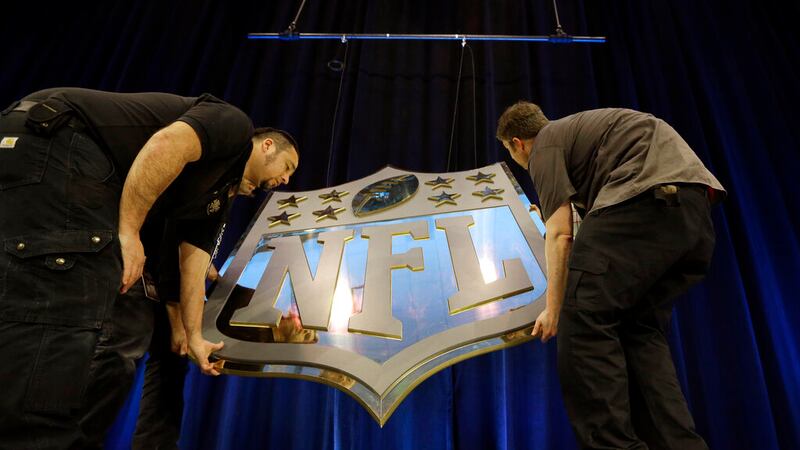 FILE - In this Feb. 4, 2016, file photo, workers hang an NFL shield on the main stage before a...