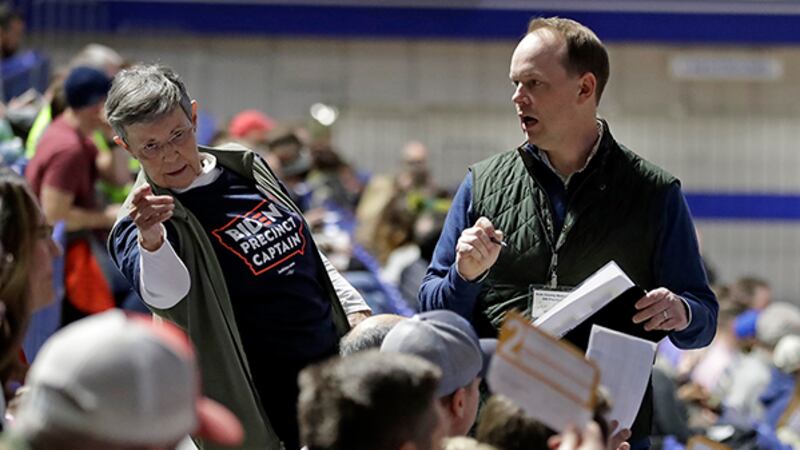 Precinct 68 Iowa Caucus voters seated in the Biden section hold up their first votes as they...