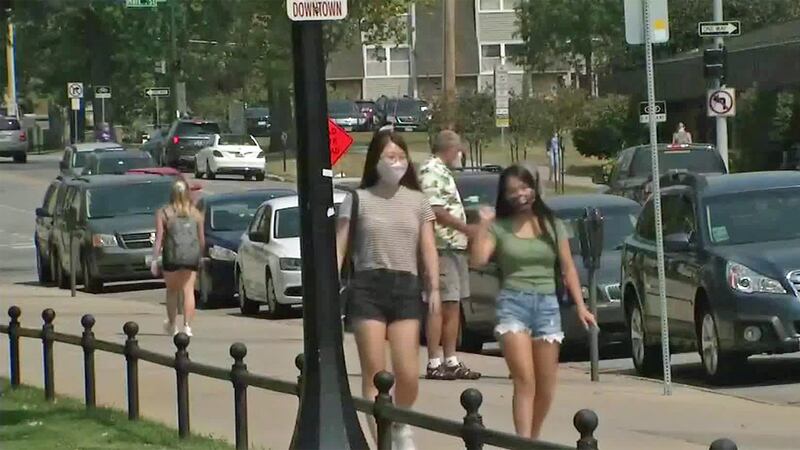 People walk along a sidewalk in Iowa City on the first day of fall classes for the University...