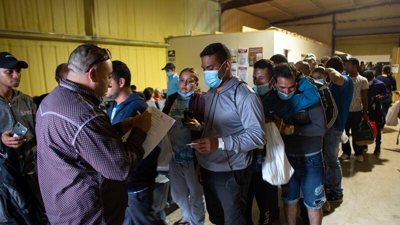 FILE - People line up for a commercial bus that will take them to the San Antonio airport at a...