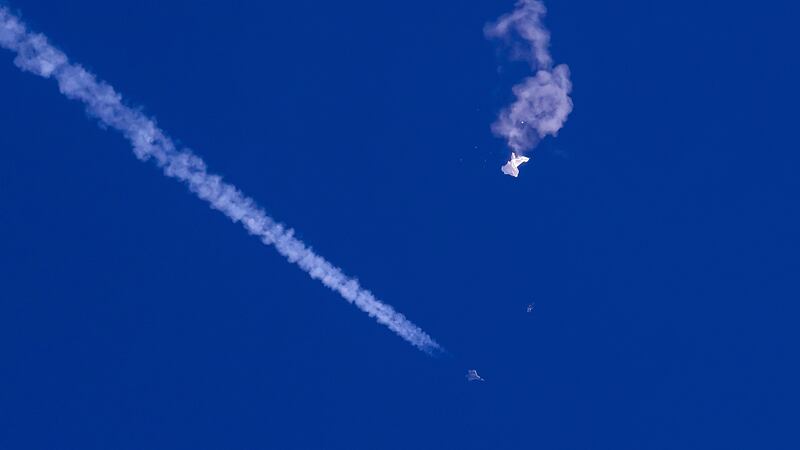FILE - A fighter jet flies past the remnants of a large balloon after it was shot down above...