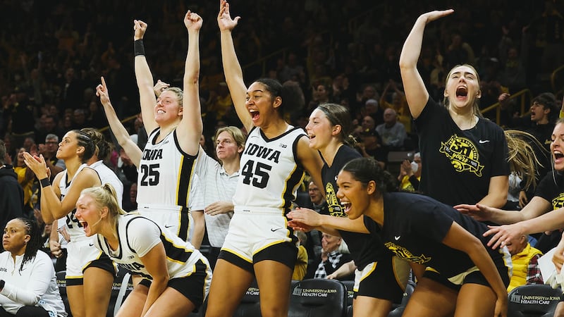 Players on the University of Iowa women's basketball team celebrate on the bench during their...