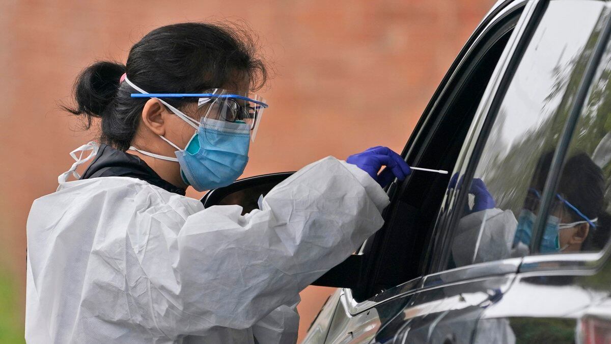 A medical worker prepares to administer a COVID-19 swab at a drive-through testing site in...